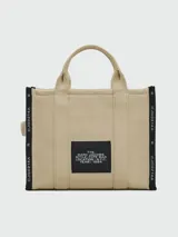 Bolso tote Marc Jacobs modelo The Jacquard, confeccionado en tejido de lona negro con detalles en blanco. Presenta el logo de la marca y la inscripción 'THE TOTE BAG' en el frente, con doble asa superior y correa ajustable extraíble.