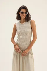 Vestido midi sin mangas confeccionado en lino color beige, con cuerpo superior ajustado mediante frunces elásticos y falda amplia con caída fluida.