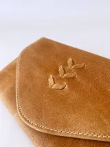 Billetera tipo sobre confeccionada en cuero color camel, con solapa en punta y detalle de costura decorativa en forma de espiga. Cuenta con cierre de broche y monedero externo.