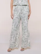 Pantalón palazzo de tiro alto y corte amplio, marca Allie Rose, con estampado botánico de hojas verdes sobre fondo blanco. Presenta cintura elastizada fruncida con cordón de ajuste y bolsillos laterales.