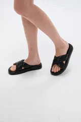 Sandalias planas color negro con tiras acolchadas cruzadas en el empeine y suela de goma con plataforma baja.