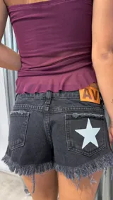 Short de jean negro con ruedo desflecado, tiro bajo y detalle de estrella blanca estampada en el bolsillo trasero derecho. Incluye etiqueta de cuero con logo en la parte posterior.