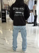 Canguro negro oversize de felpa, con capucha, bolsillo tipo canguro y diseño estampado en la espalda con gráficos estilo streetwear y texto en blanco.