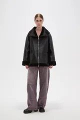 Campera de cuero sintético con interior y detalles de piel sintética en cuello, puños y ruedo. Presenta cierre frontal completo y diseño de corte holgado.