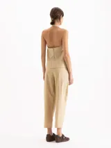 Pantalón slouchy de poplín color beige, de calce regular y largo al tobillo, con tablas en el delantero y ruedo que aportan volumen, bolsillos laterales y cierre con botones tipo honguito.
