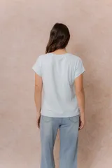 Remera básica color celeste, de corte relajado, cuello redondo y mangas cortas con hombro caído y dobladillo.