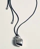 Collar largo con cordón negro ajustable y dije metálico de diseño orgánico y minimalista.