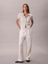 Chomba Calvin Klein de manga corta en color blanco, con cuello clásico, cierre frontal con botones y diseño de jacquard con estampado integral.