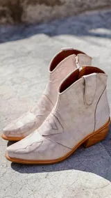 Botas cortas de cuero sintético color beige con detalles de costuras estilo western.