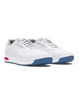 Championes Under Armour modelo Court 96, de diseño urbano y deportivo. Presentan una parte superior de cuero blanco con detalles perforados, entresuela blanca con inserción roja en el talón y suela de goma azul.