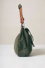 Bolso tipo tote en color verde oliva, confeccionado en tela técnica arrugada. Cuenta con una correa de hombro estilo cuerda en tonos naranja y azul con nudos decorativos, y una cadena decorativa de eslabones de resina en color carey. Presenta cierre superior y detalles de cordones laterales.