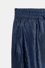 Pantalón de tiro alto de tela satinada color azul marino, con bolsillos frontales, cintura ajustable con cordones y puños elásticos en los tobillos.