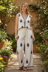 Conjunto de pantalón y chaleco blancos con bordados rojos. El chaleco es corto, con escote en V y se ata en el frente. El pantalón es recto y de tiro alto.