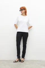 Remera blanca de manga 3/4 con cuello redondo y botones metálicos decorativos en los hombros.