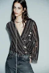 Body negro con escote en V cruzado, mangas largas acampanadas y apliques de lentejuelas.