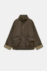 Chaqueta encerada color marrón con efecto lavado, cuello subido y manga larga. Cuenta con bolsillos frontales de plastrón y cierre de cremallera oculto por solapa con botones a presión. Los puños reversibles dejan ver un forro interior con estampado a cuadros.