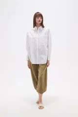 Camisa de algodón con diseño de rayas verticales, corte holgado, cuello camisero, cierre frontal con botones, mangas largas con puños y un bolsillo frontal con rayas horizontales.