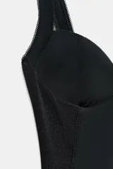 Vestido midi negro con escote corazón, aros y tirantes anchos. Presenta una combinación de tejidos con laterales de malla transparente, corte ajustado y bajo recto.