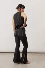 Jean oxford color negro con elastano, tiro alto, bolsillos traseros con bordes desflecados, recortes en las rodillas y tajos laterales en el ruedo.