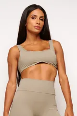 Top deportivo color verde oliva, con escote cuadrado y curvatura frontal. Incluye forro interno y apertura para almohadillas removibles.