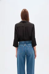 Blusa de poliéster color negro, con cuello en V, corte holgado y mangas tres cuartos.