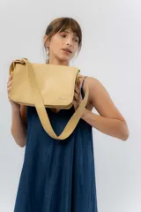 Bandolera amplia y moderna de eco cuero texturado color tostado, con solapa frontal, imán oculto, correa regulable y logo metálico de la marca Peach.
