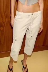 Pantalón capri de tiro medio con bolsillos cargo laterales, cierre frontal con cremallera, botón metálico y cordón ajustable en la cintura.