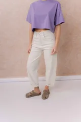 Jeans de tiro alto y silueta barrel, color crudo, con cinco bolsillos, presillas para cinturón y cierre frontal con botón y cremallera. Presenta diseño de pierna amplia con leve entalle hacia el ruedo y dobladillo vuelto.