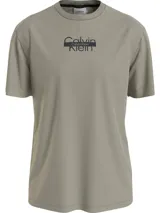 Remera de algodón color verde oliva, con cuello redondo y mangas cortas. Presenta un diseño gráfico central con el logotipo de Calvin Klein en negro, superponiendo el texto en dos líneas con una barra horizontal.