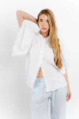 Camisa de lino color blanco, con cuello clásico y cierre frontal de botones. Presenta mangas cortas y amplias con diseño acampanado y un calce holgado.
