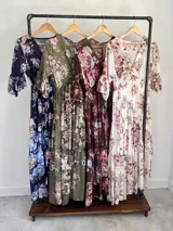 Vestido midi de estilo campesino confeccionado en organdí con estampa floral chintz de estilo romántico. Presenta escote en V cruzado, cintura completamente elastizada y falda larga con volados en niveles. Las mangas son tres cuartos con volados en los puños.