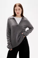 Sweater de tejido de punto en color gris, con cuello en V y diseño de calce relajado. Presenta mangas largas con puños acanalados y ruedo también acanalado.