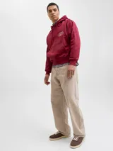 Pantalón de corte baggy y tiro alto, confeccionado en algodón con acabado lavado en tono beige. Presenta una silueta amplia y relajada, con cierre frontal de cremallera y bolsillos laterales y traseros.