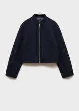 Chaqueta tipo bomber de color negro con cuello redondo y cierre frontal con cremallera metálica. Presenta un diseño recto de manga larga y cuenta con forro interior.