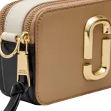 Cartera bandolera Marc Jacobs modelo The Snapshot, color tostado con herrajes dorados y logo frontal metálico. Incluye correa ajustable con diseño de cinta tejida y cierre superior.
