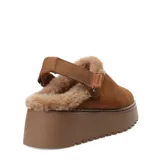 Zueco de mujer color marrón camel, confeccionado en gamuza con forro interior de piel sintética. Presenta una suela de plataforma dentada en tono marrón y una tira trasera ajustable con cierre de velcro.