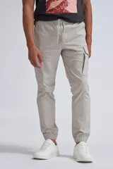 Pantalon tipo cargo jogger color gris claro, con cintura elástica ajustable mediante cordón, bolsillos laterales tipo cargo y puños elásticos en los tobillos.