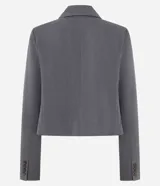 Blazer corto de sastrería color gris oscuro, con solapas estructuradas, manga larga y corte ajustado. Se combina con un top de encaje negro y pantalón ancho a juego.