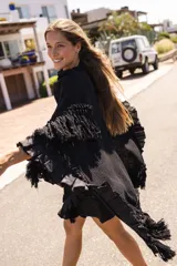Ruana tejida artesanalmente con diseño de red, color negro, con detalles de volados y flecos en los bordes.