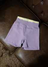 Calza corta deportiva tiro alto, color lila con pretina ancha de contraste en color verde lima.