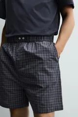 Set de pijama compuesto por una remera lisa de manga corta con cuello redondo y una bermuda a cuadros con bolsillos laterales y cintura elástica.