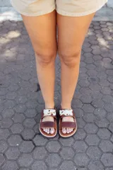 Sandalias bajas de cuero color marrón con doble tira, una lisa y otra con estampado animal print de vaca. Hechas a mano en Uruguay.