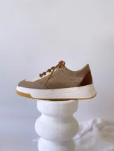 Championes de cuero color visón con cordones marrones, suela blanca y base color caramelo.