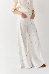Pantalon de corte wide leg y tiro alto, color rosado con estampado de motivos deportivos como pelotas de fútbol y raquetas de tenis. Cuenta con cierre frontal con botón y bolsillos laterales.