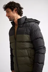 Campera puffer de nylon con diseño bicolor en negro y verde oliva. Cuenta con cierre frontal completo, capucha desmontable y logo de la marca estampado en el pecho.