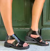 Sandalias negras de cuero con textura escamada, corte asimétrico y suela track.
