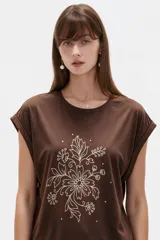 Remera negra de algodón, con cuello redondo, mangas cortas holgadas con vuelta y estampa floral grande en el pecho.