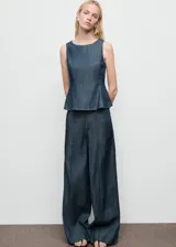 Pantalón de tiro alto con diseño wide leg, confeccionado en tejido de algodón y lyocell estilo denim. Presenta costuras verticales decorativas, bolsillos laterales y cierre oculto con botón, gancho y cremallera.