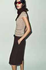 Camiseta de corte ajustado con escote redondo y manga corta, confeccionada en tejido de punto con lana. Presenta un diseño de rayas horizontales en tonos beige y marrón.