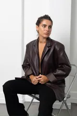 Blazer de cuero sintético negro con solapas clásicas, cierre frontal con botones y corte recto.